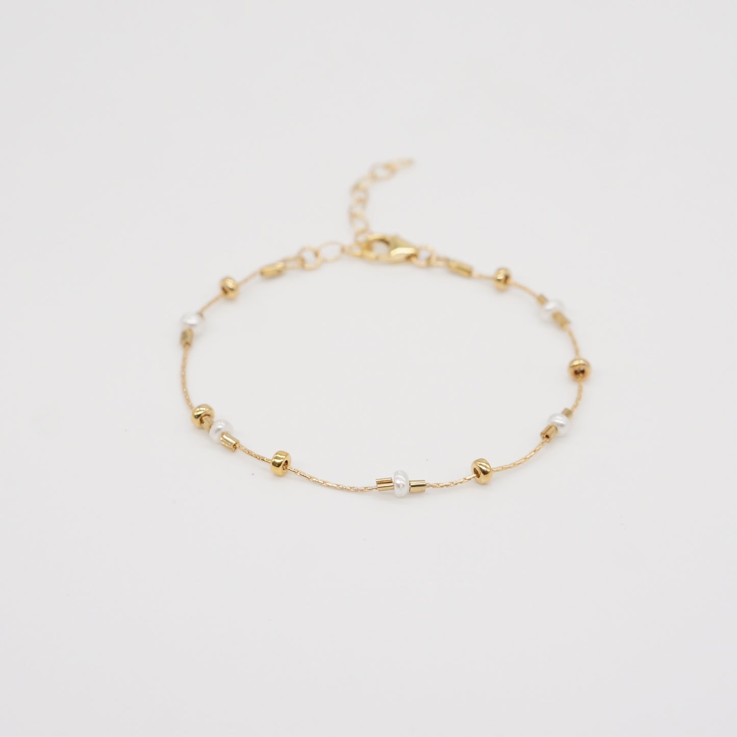 A dainty take on a pearl bracelet. Gold beads float freely in between dainty pearls. 1" extender 14k gold fill made in Los Angeles pearls vary in shape and size