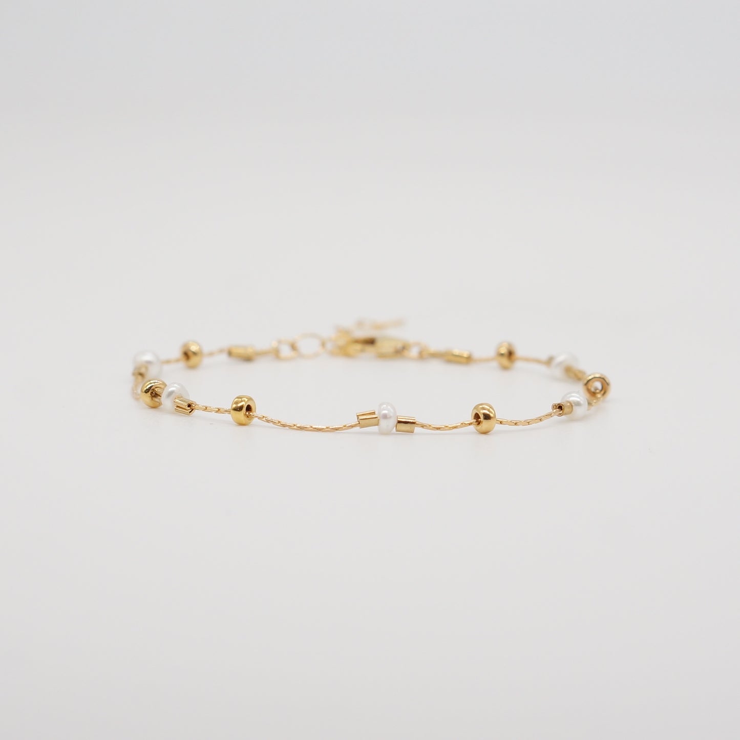 A dainty take on a pearl bracelet. Gold beads float freely in between dainty pearls. 1" extender 14k gold fill made in Los Angeles pearls vary in shape and size